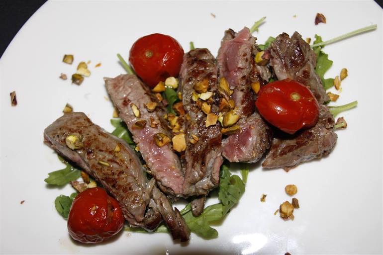 Tagliata di manzo con pomodorini appassiti, rucola e pistacchi